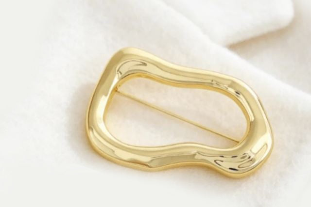 Gylden broche i asymmetrisk design